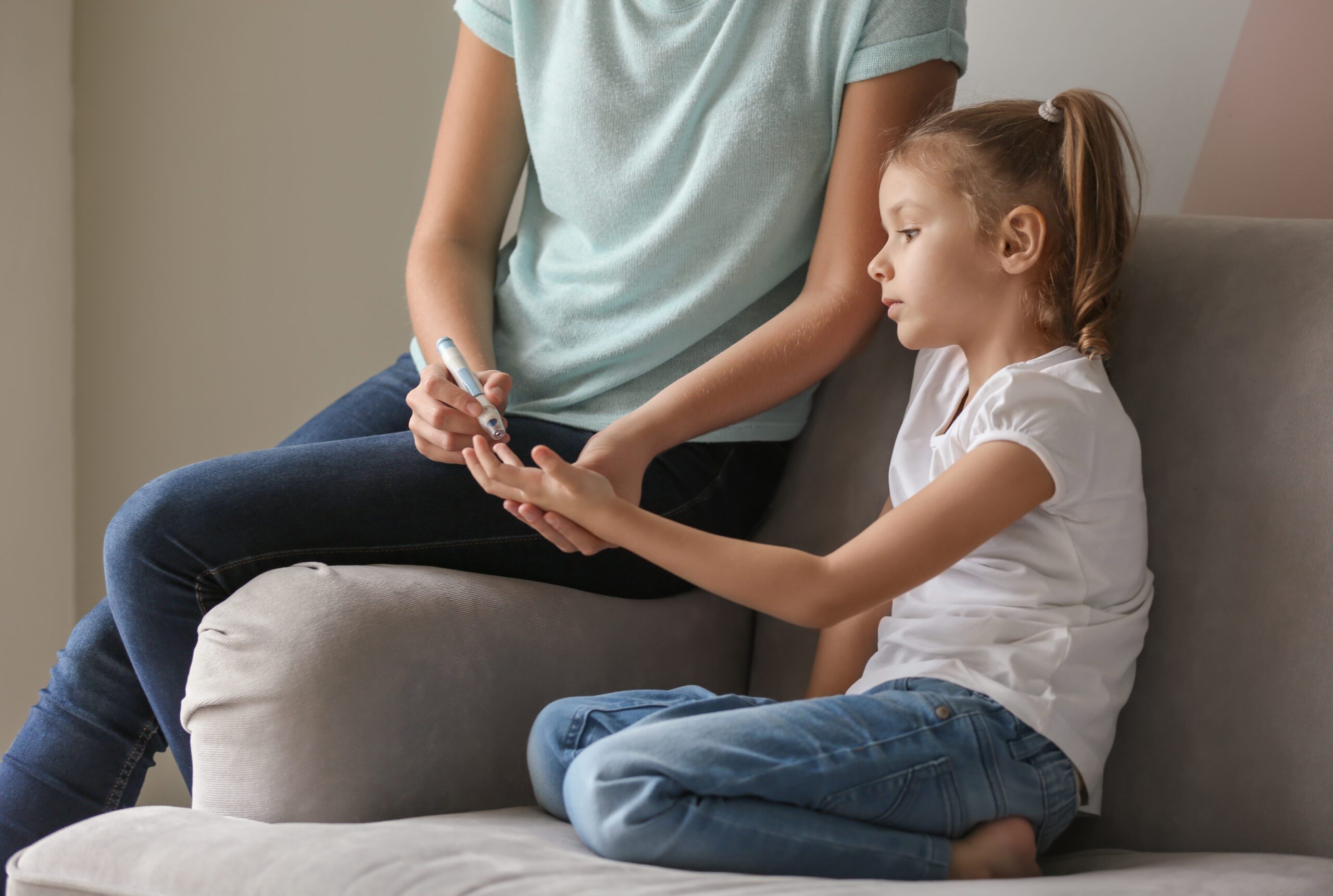 Vrouw test de bloedwaarden van haar dochter met diabetes met een lancet en pen